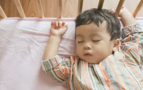 Little boy toddler adorably sleeping in his baby cot