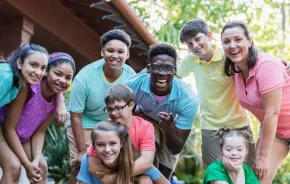 Group of teens and camp staff smiling together outdoors at camp