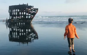 boy looking at the peter iredale shipwreck while camping in Oregon