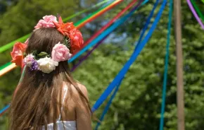 A girl with flowers in her hair participates in a May Day pole dance