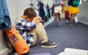 little boy sitting in corridor anxious at end of school 