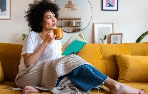 woman sitting on a couch with a cup of coffee and a book
