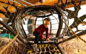 young child climbing in a rope climber at Hands on Children's Museum, which is hosting spring break activities this weekend