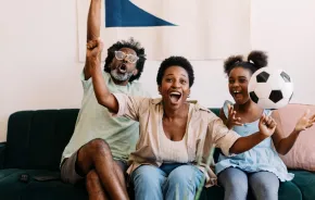 A family excitedly cheers while watching a FIFA World Cup soccer game