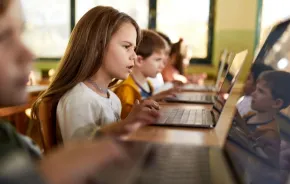 young girl studying on laptop in classroom