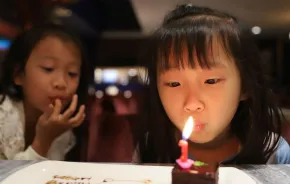 little girl blowing a birthday candle