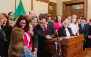 Gov. Bob Ferguson handing over his pen to a child