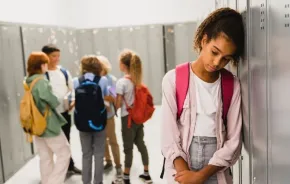student leaning against locker, looking sad, worried about end of the school year