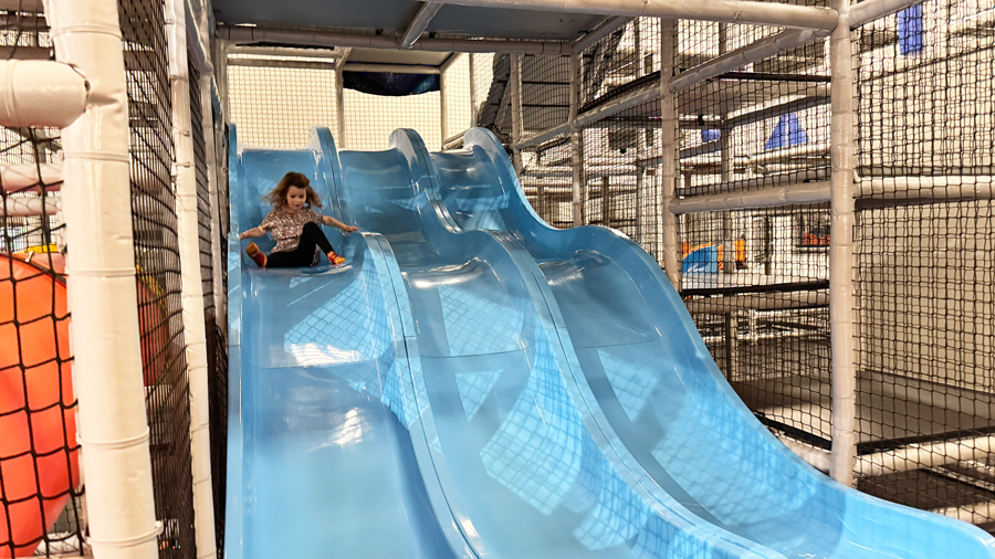girl sliding down the triple blue slides at Nick's Magnificent indoor playground in Issaquah