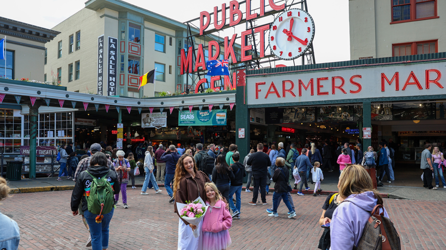family smiling in front of the Pike Place Market sign, a Seattle attraction for kids