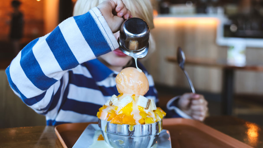 Kid pouring condensed milk on a bingsu from Lumi