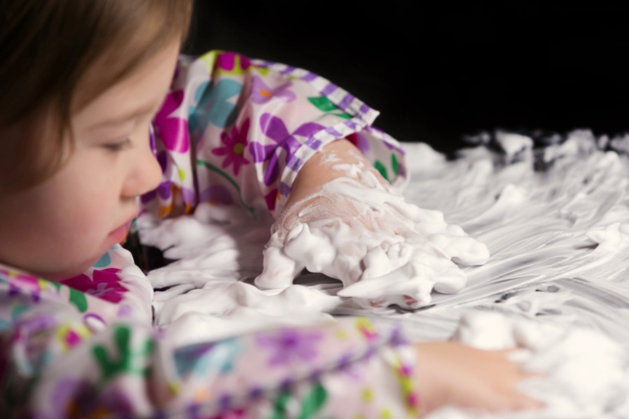 Little girl playing with foamy cream