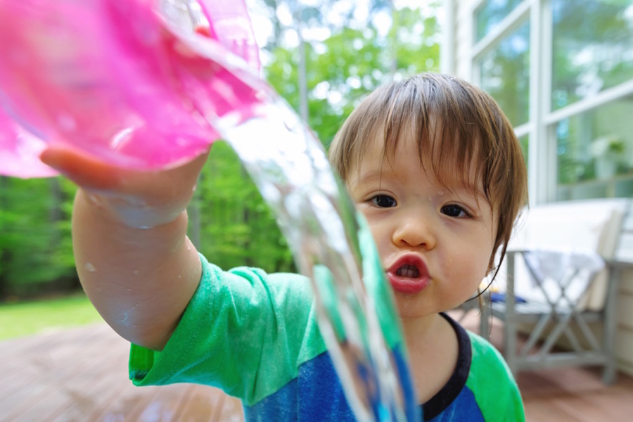 Little boy playing with water outside on a warm day