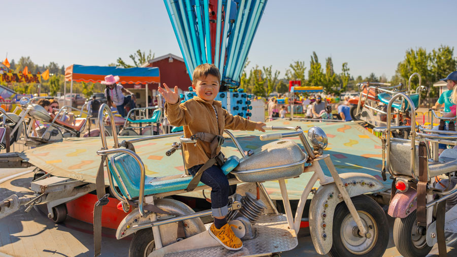kid sitting on a ride at the Washington State Fair waving