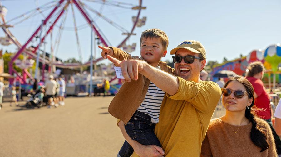 family at Washington state fair pointing and looking at rides