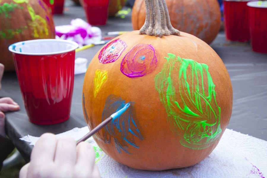 Child painting a pumpkin with bright paint
