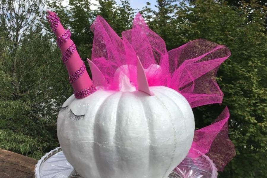 Pumpkin decorated like a unicorn with a pink horn