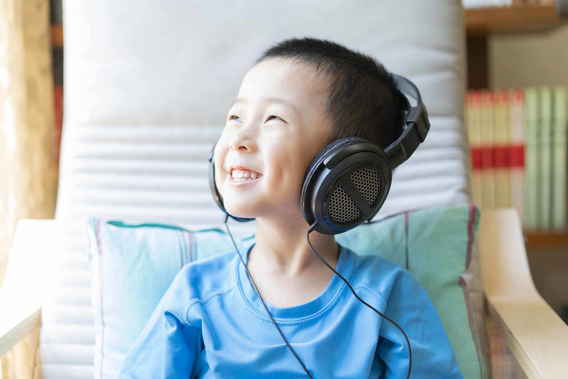 young boy wearing headphones smiling looking out window