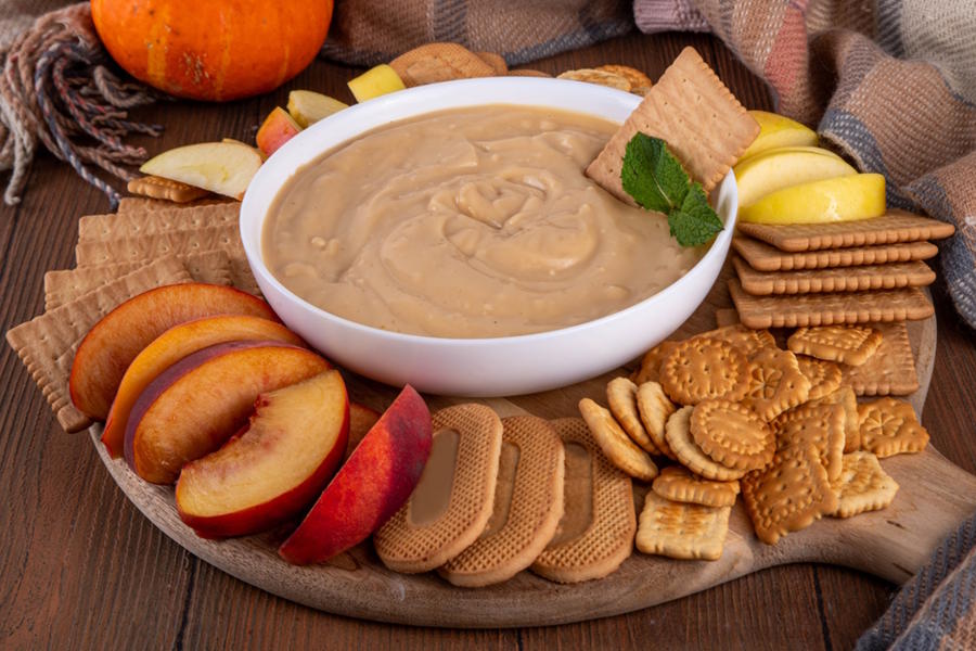 A bowl of pumpkin cheesecake dip and crackers and fruit as a Thanksgiving starter