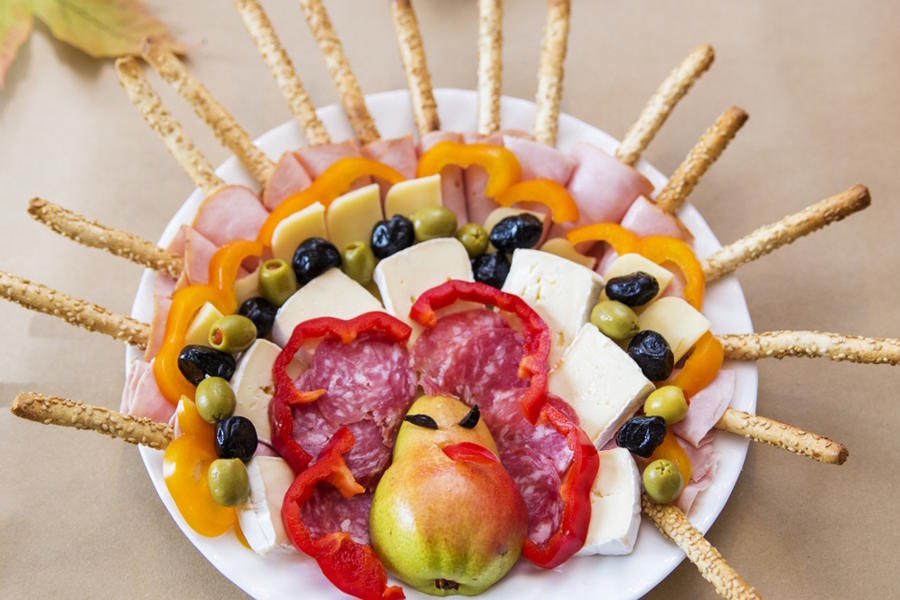 A snack tray made up of crackers, cheese and fruit shaped like a turkey