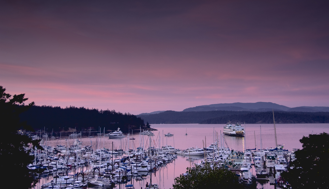 ferry sliding into friday harbor on san juan island at dusk during a purple sunset