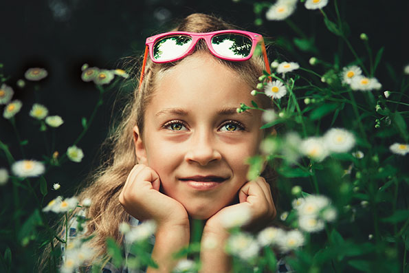 Sweet-faced young girl holds her head in her hands and daydreams in nature