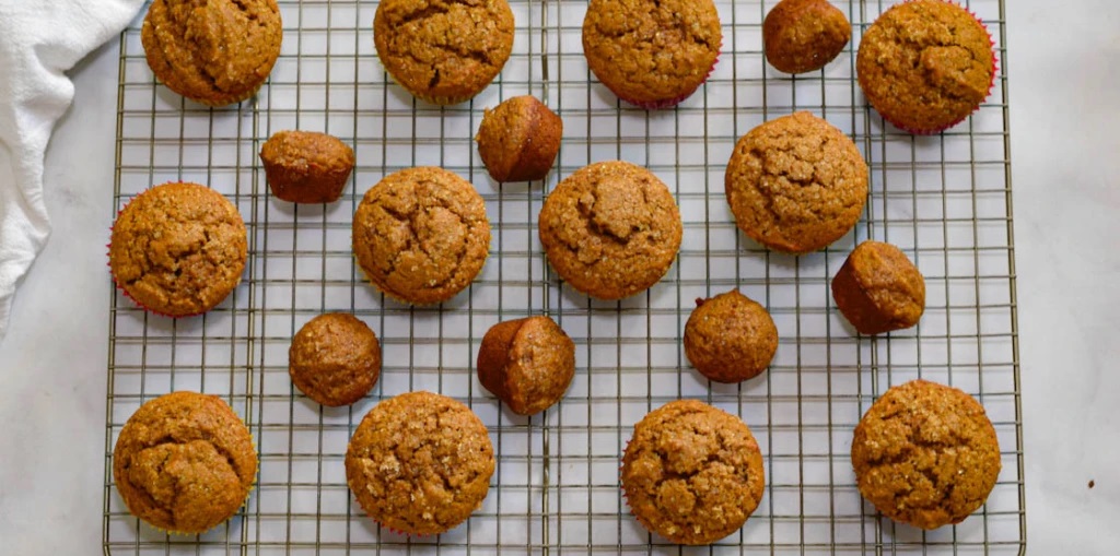 Small pumpkin muffins lined up on a baking tray