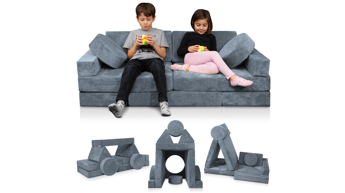 Two kids sitting on a gray modular couch that can be taken apart of built into a fort