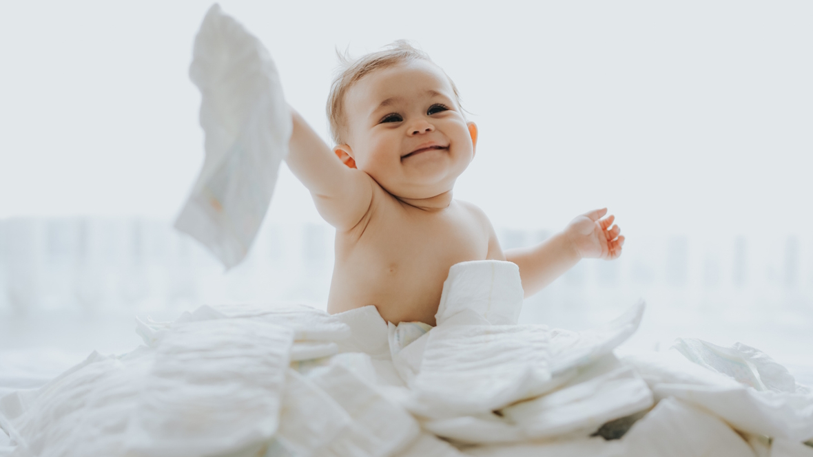 Baby sitting in a pile of diapers that came in a baby subscription box