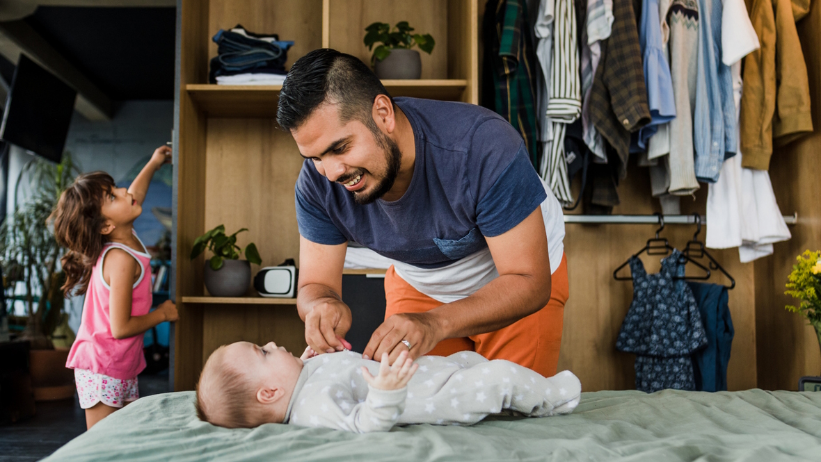 Dad getting baby dressed in a cute outfit that came in a baby subscription box
