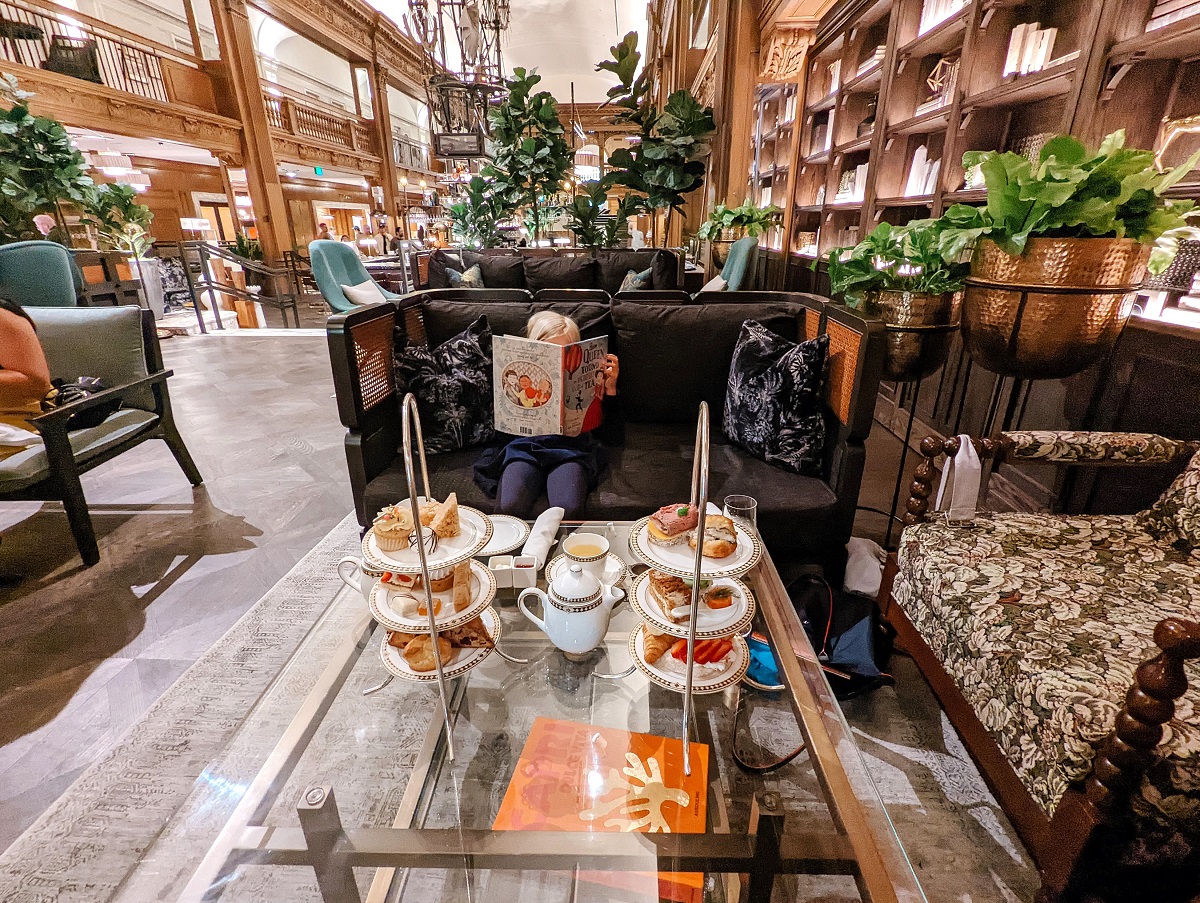A girl reads a book while enjoying afternoon tea in the lobby of Seattle's fancy Fairmont Olympic hotel