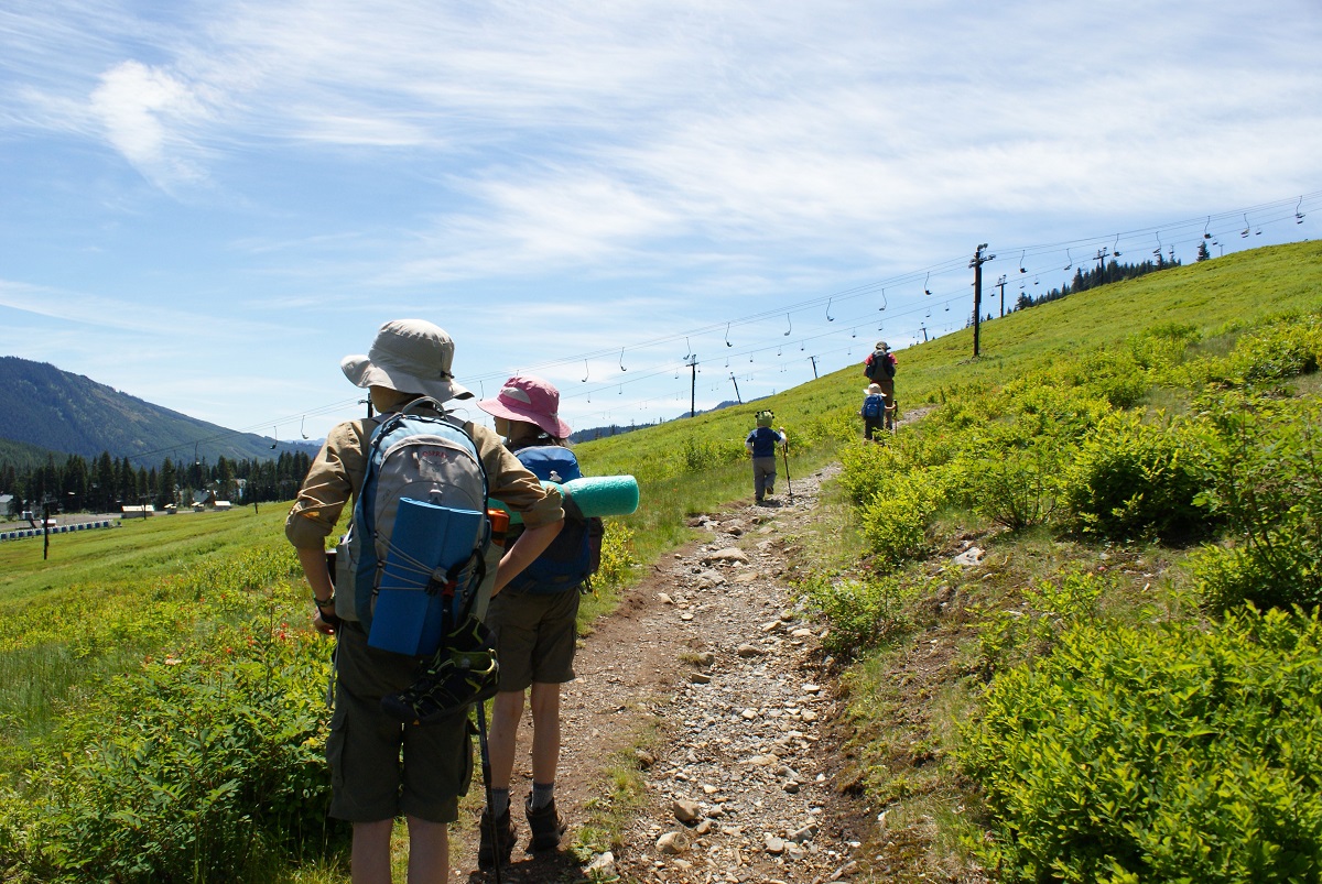 Kids with backpacks hike along the Lodge Lake trail among great wildflower hikes