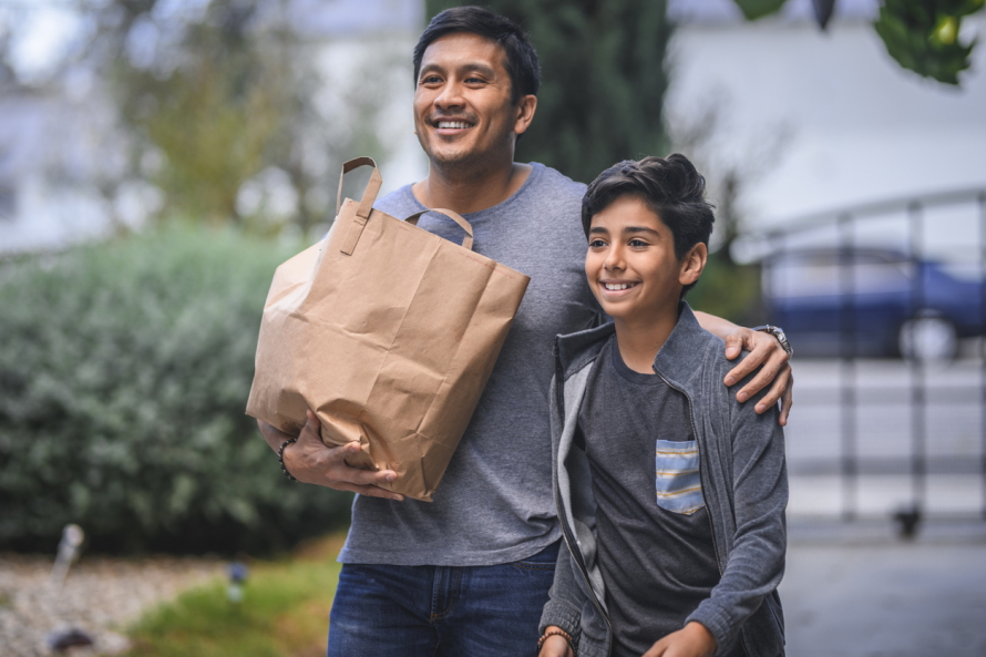 Father and son walking with a paper bag