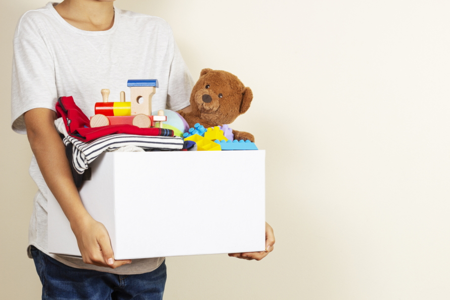 Person in a white shirt carrying box of toys 