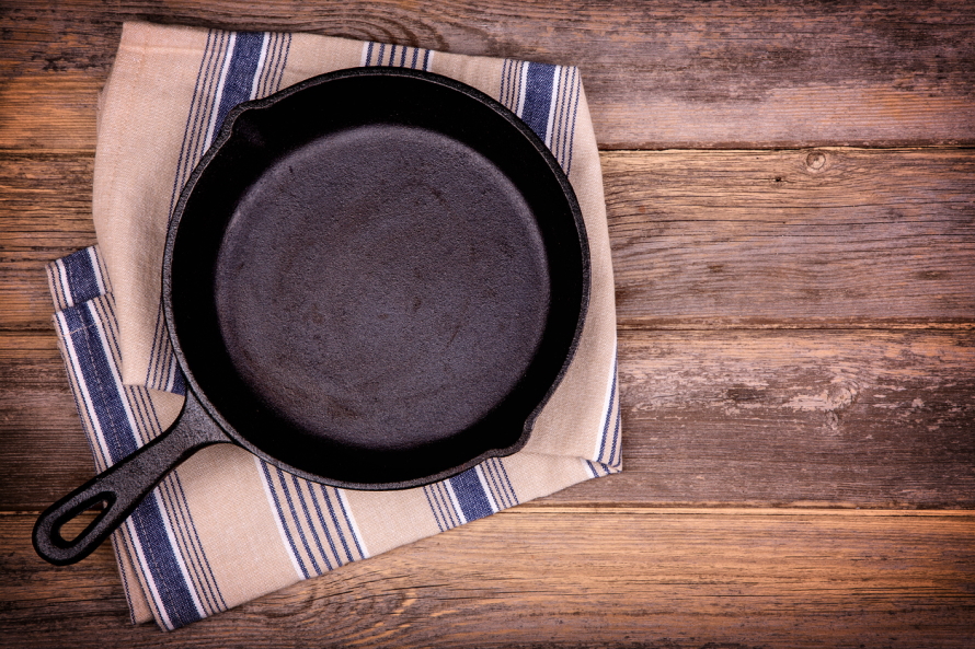 Cast iron skillet laying on a kitchen towel on a wooden countertop