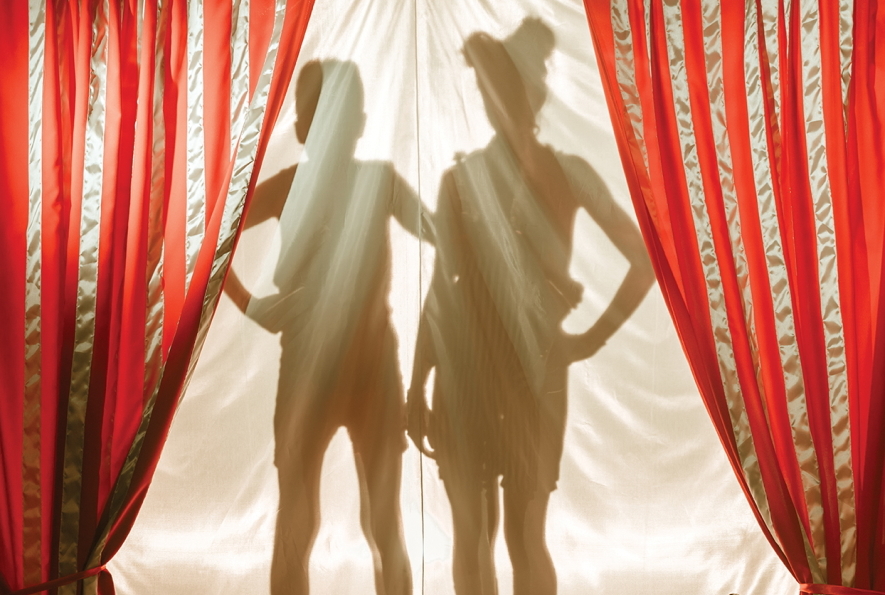 Profile of two children standing behind a curtain