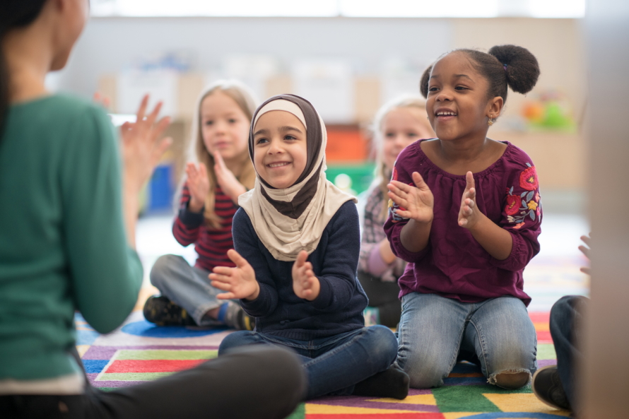 Young girls sitting on the floor smiling and clapping
