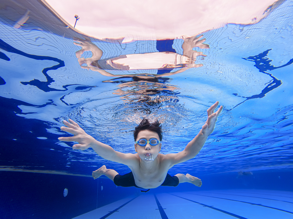 Kid with goggles swimming underwater during middle school rec swim at the Lynnwood pool