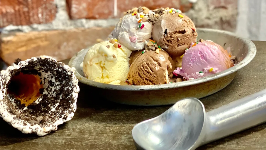 Bowl holding several scoops of ice cream with a waffle cone next to it, at Laina's one of the best ice cream in seattle shops
