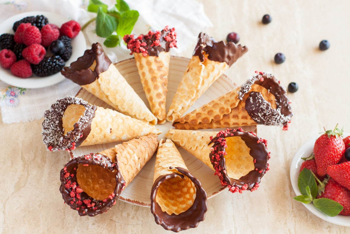 Ice cream cones dipped in chocolate and sprinkles on a plate