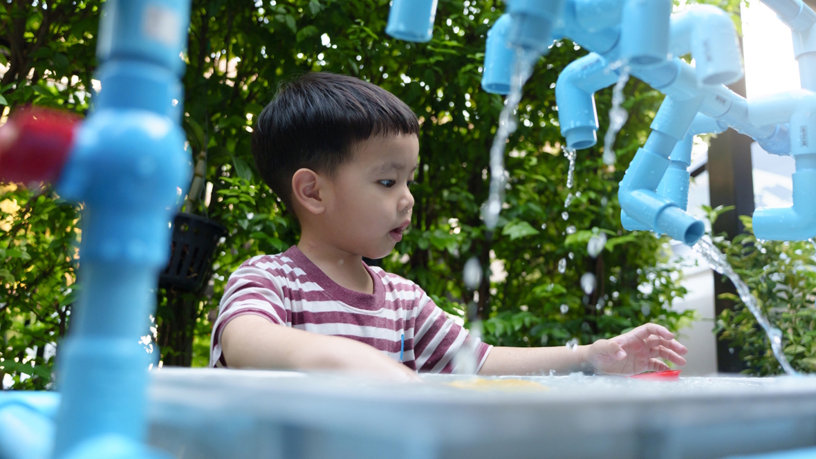 young boy playing with water outside
