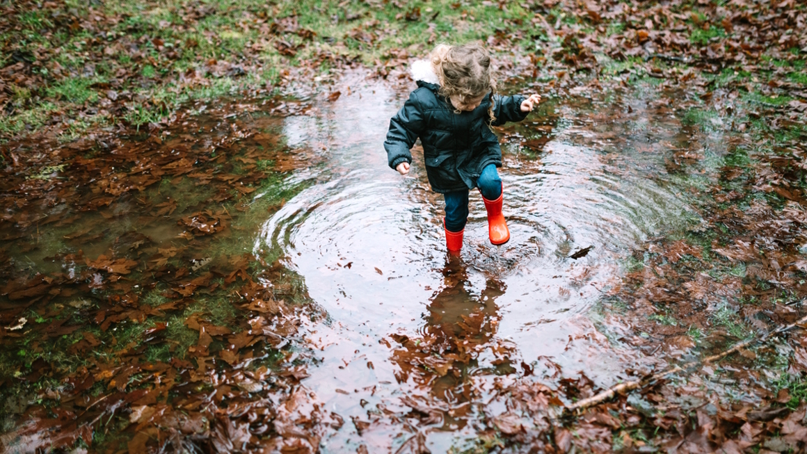 Young girl stomping in a puddle while on a kid-friendly fall hike