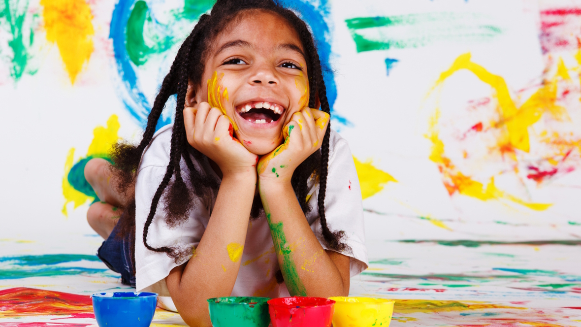 Girl smiling with paint everywhere enjoying a messy art project