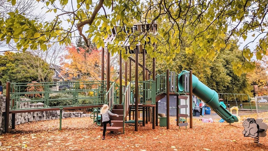 Young girl playing at Lakewood Park's playground in Seattle, a great rainy-day playground and park