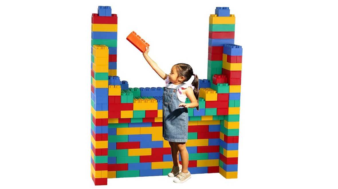 A girl building a tall tower with large blocks