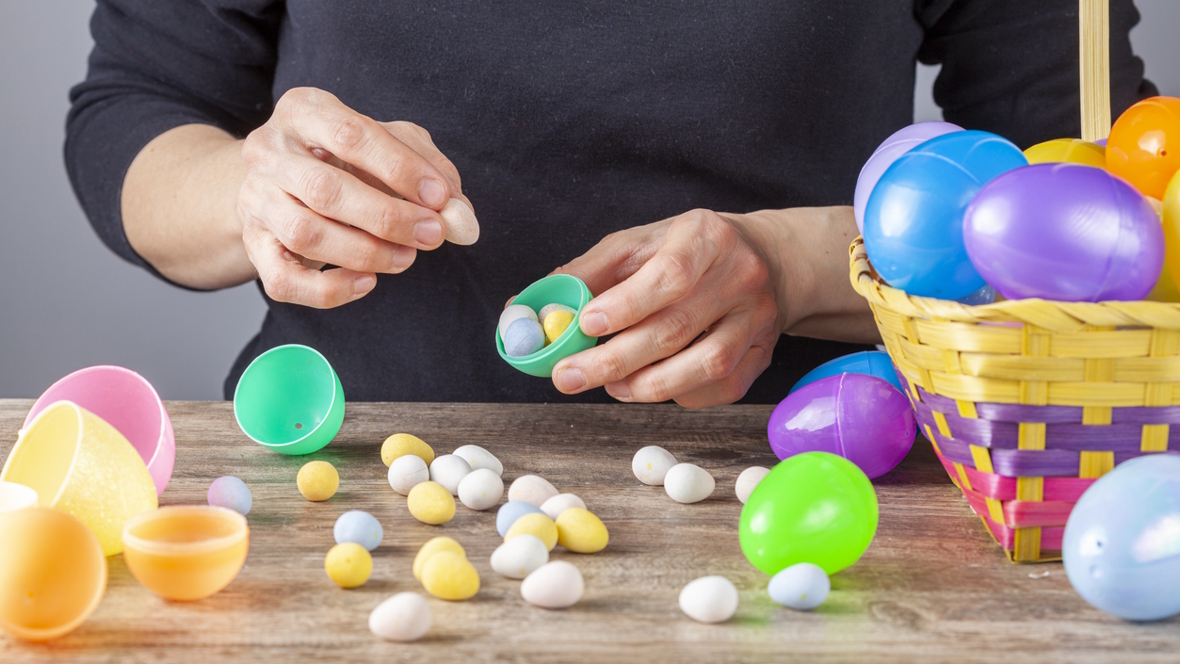 adult putting candy into a plastic Easter egg