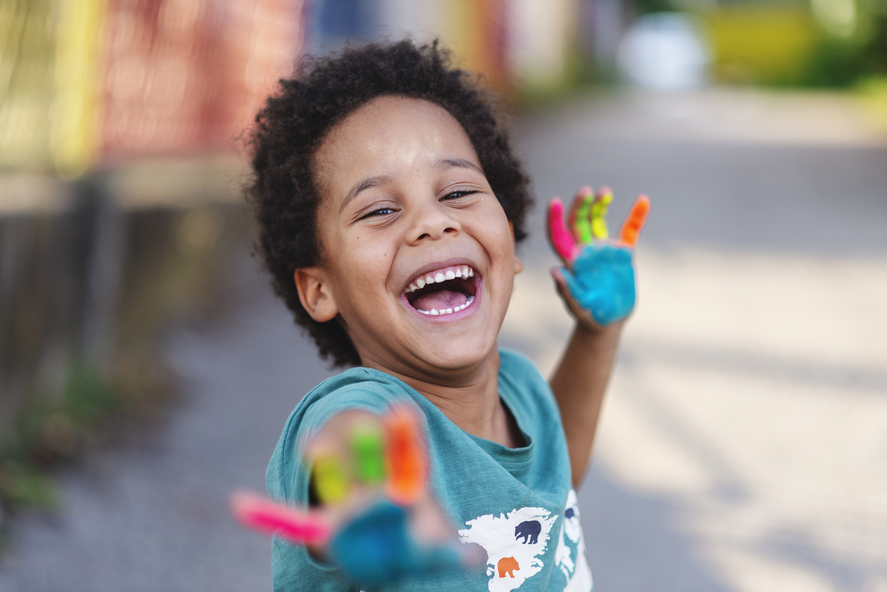 happy little boy with rainbow paint on his palms