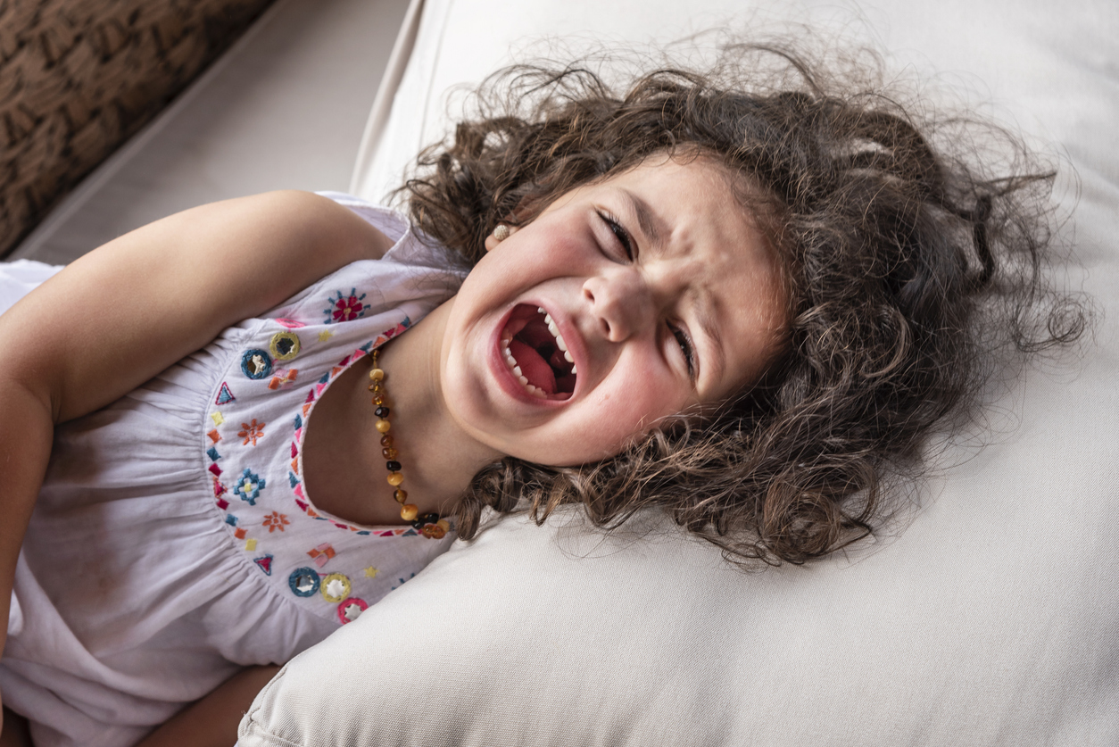 girl lying on her side screaming in a tantrum