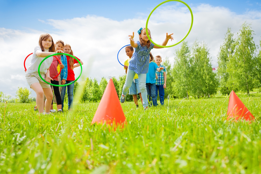 kids tossing hoops at orange cones in a field