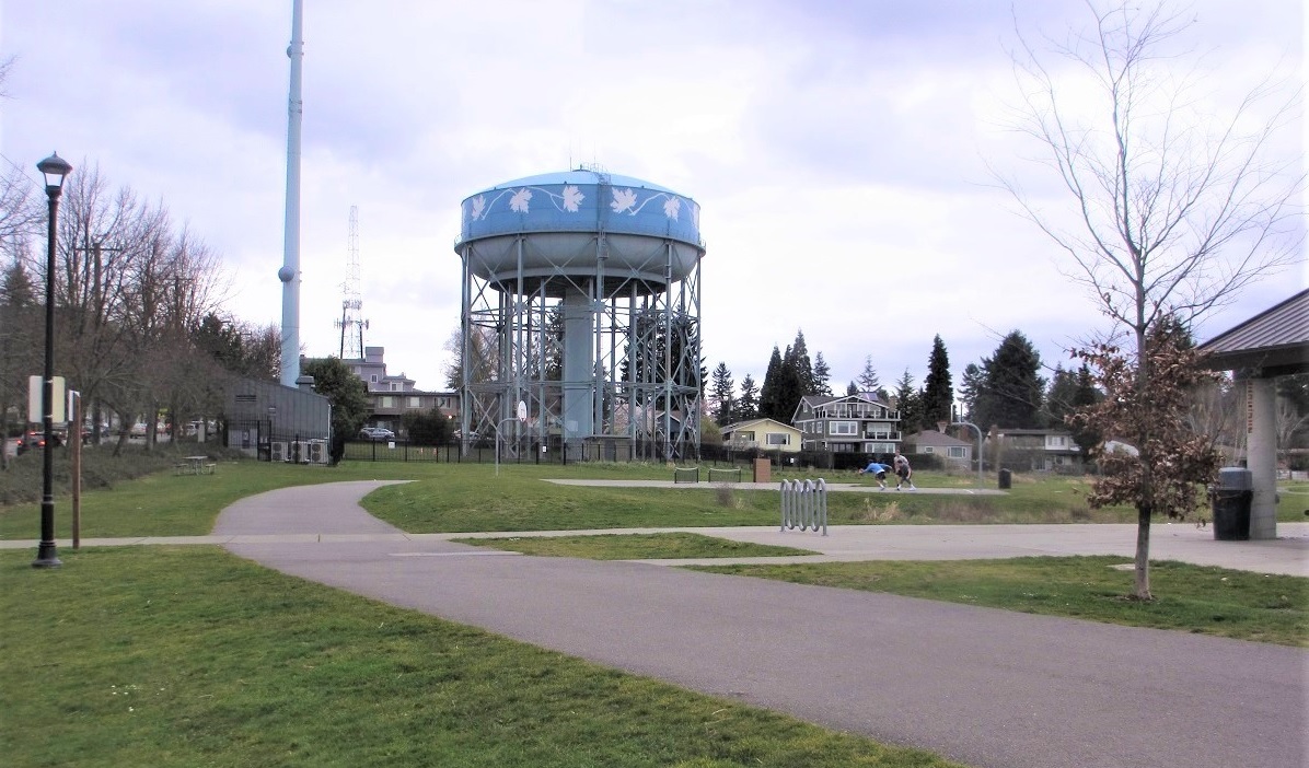 View of the bike path encircling the upper level of Seattle's Maple Leaf Reservoir Park with the blue water tower in the frame